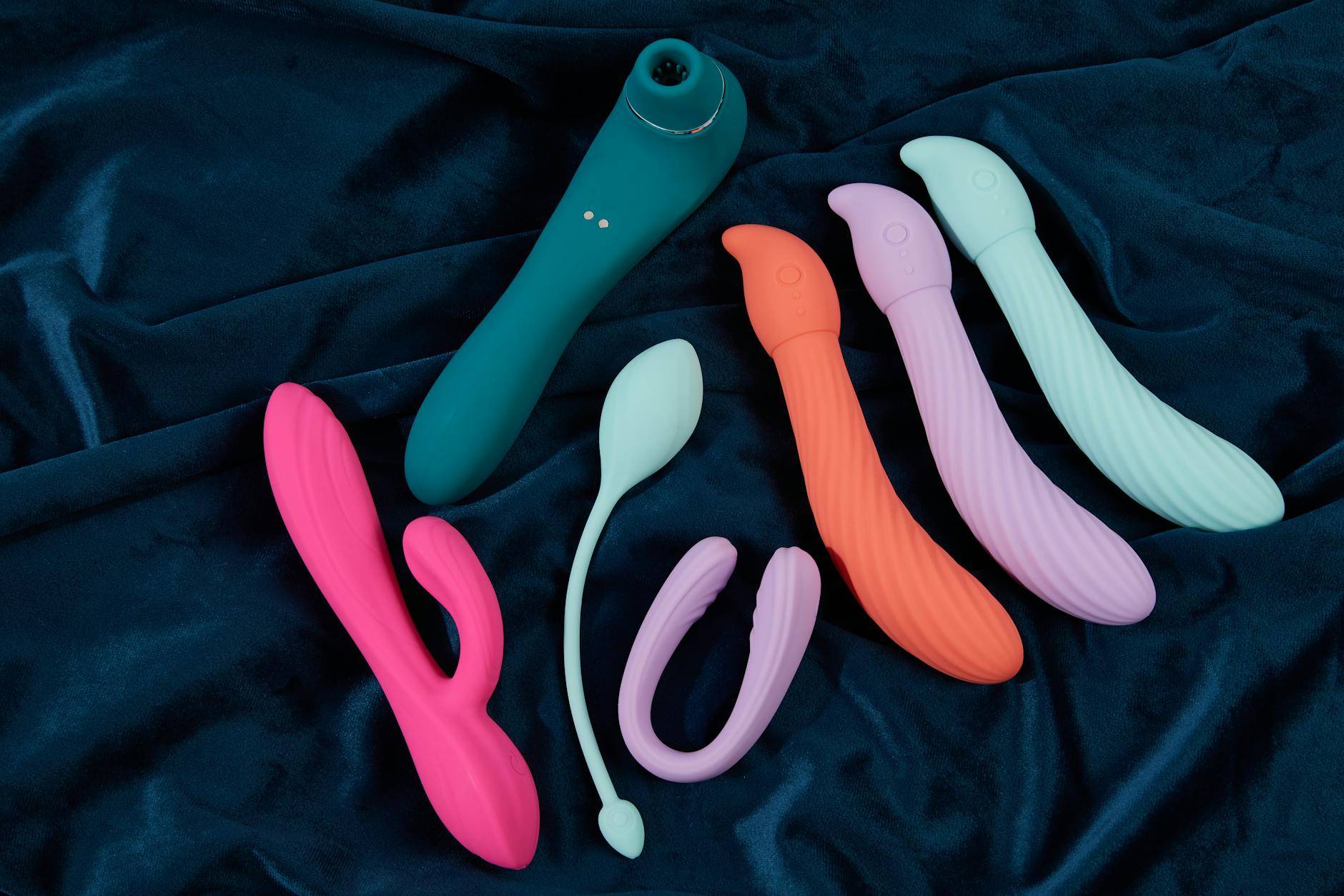 Eine Hand hält einen orangefarbenen Vibrator gegen einen minimalistischen violetten Hintergrund und zeigt moderne Sinnlichkeit