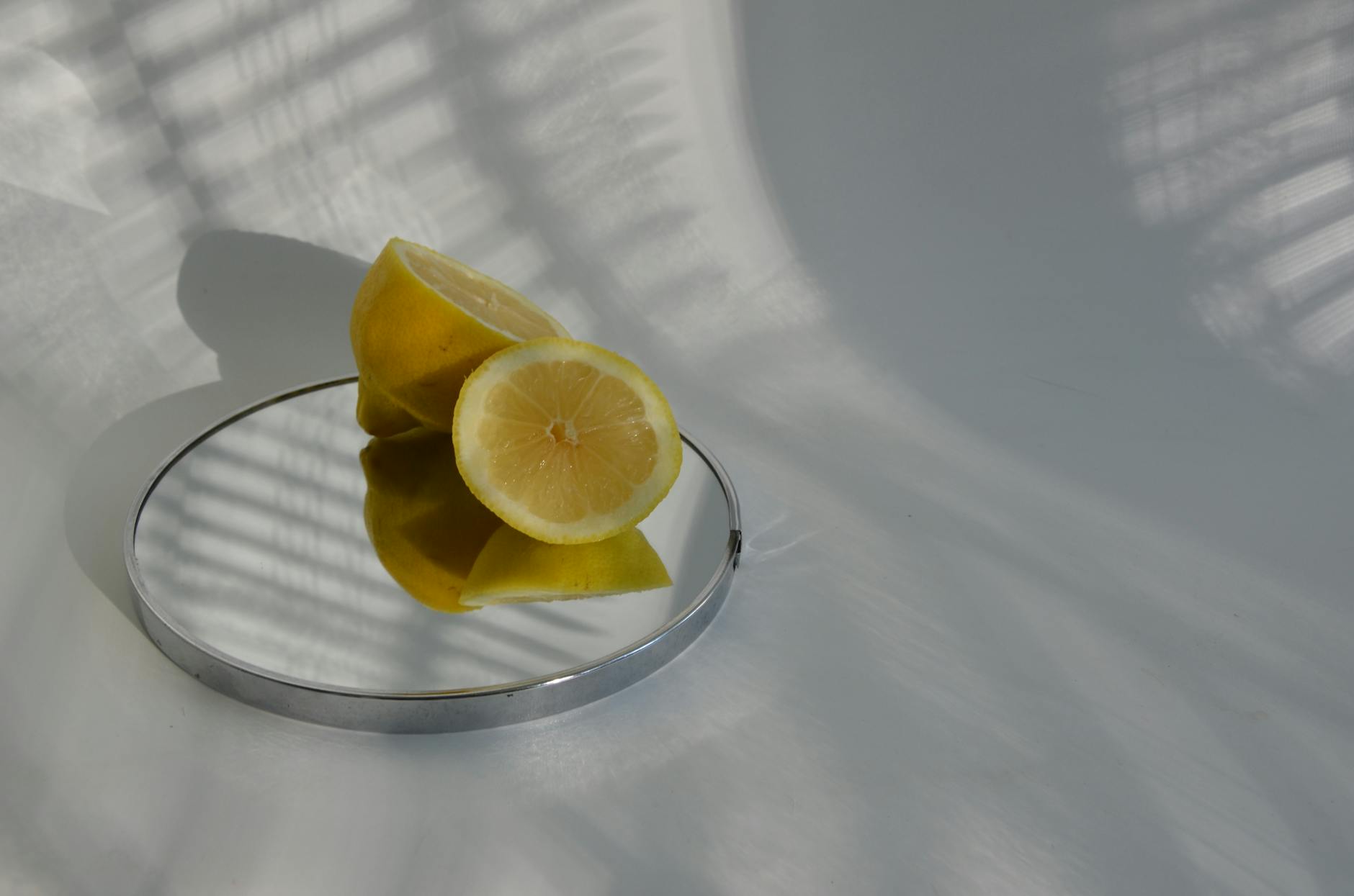 Frische Zitronen auf weißem Teller vor gelbem Hintergrund, symbolisierend Frische und Erneuerung
