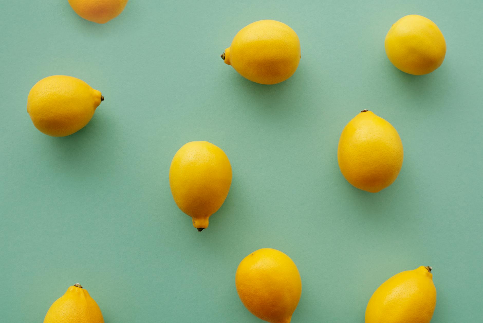 Bright yellow lemons arranged on a pastel green background, symbolizing fresh pleasure and vitality in your thirties.
