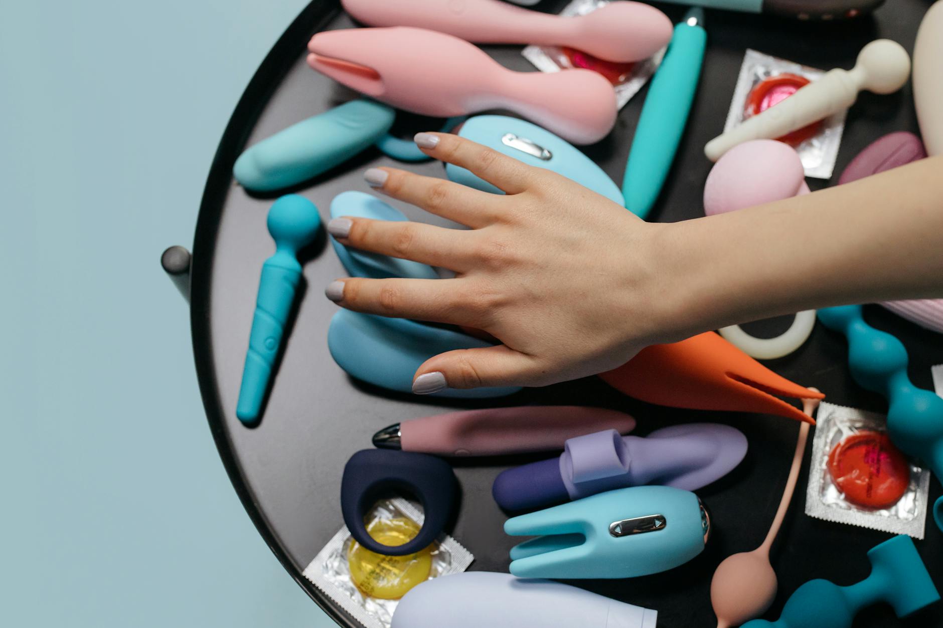 A hand holding an orange vibrator against a minimalistic purple backdrop