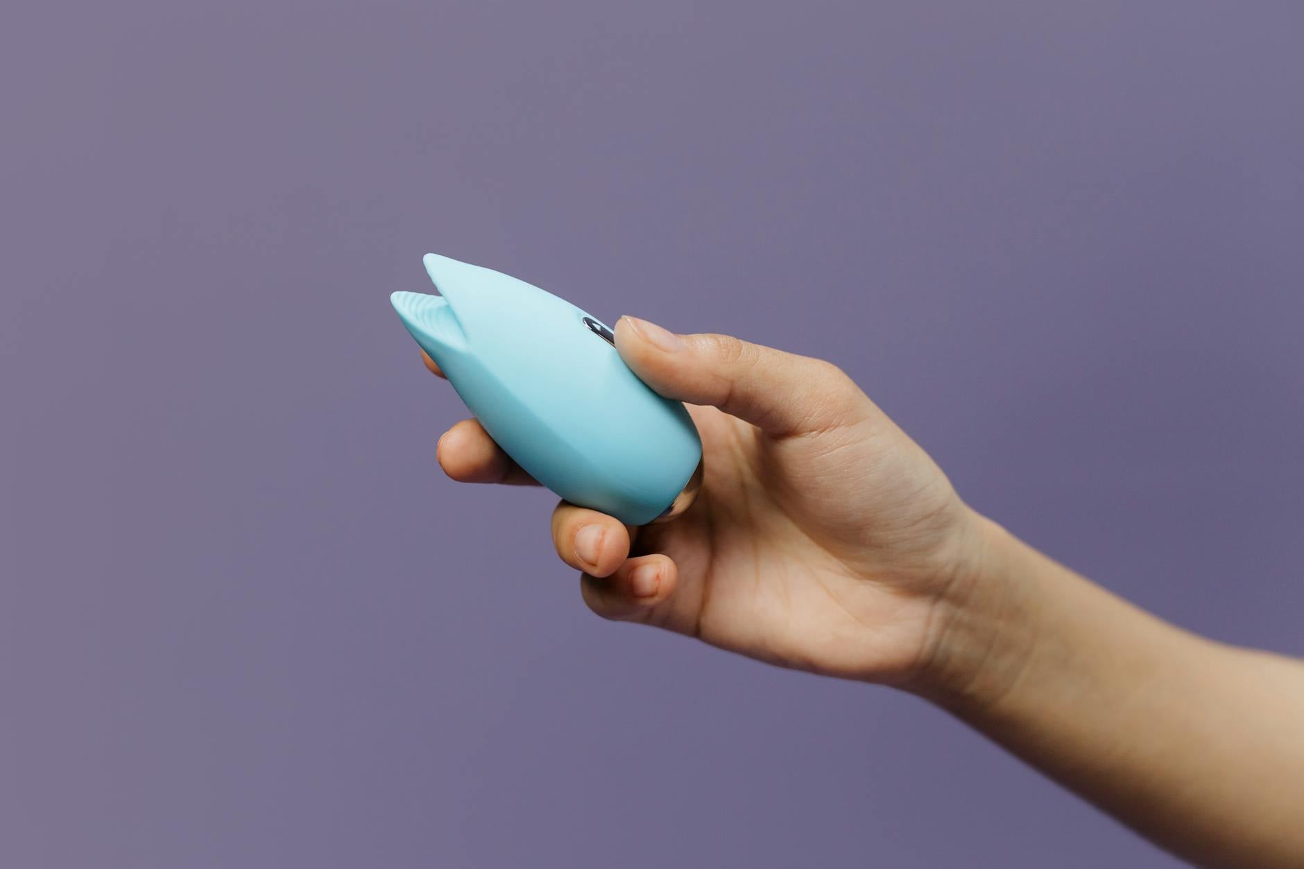 Woman holding a blue and pink vibrator thoughtfully