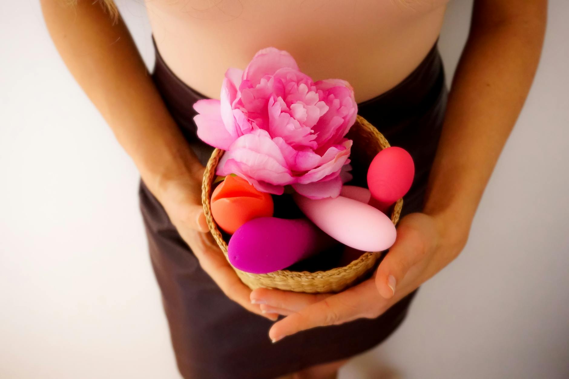 A collection of colorful vibrators and wellness toys in a basket, representing diverse approaches to pleasure and self-discovery